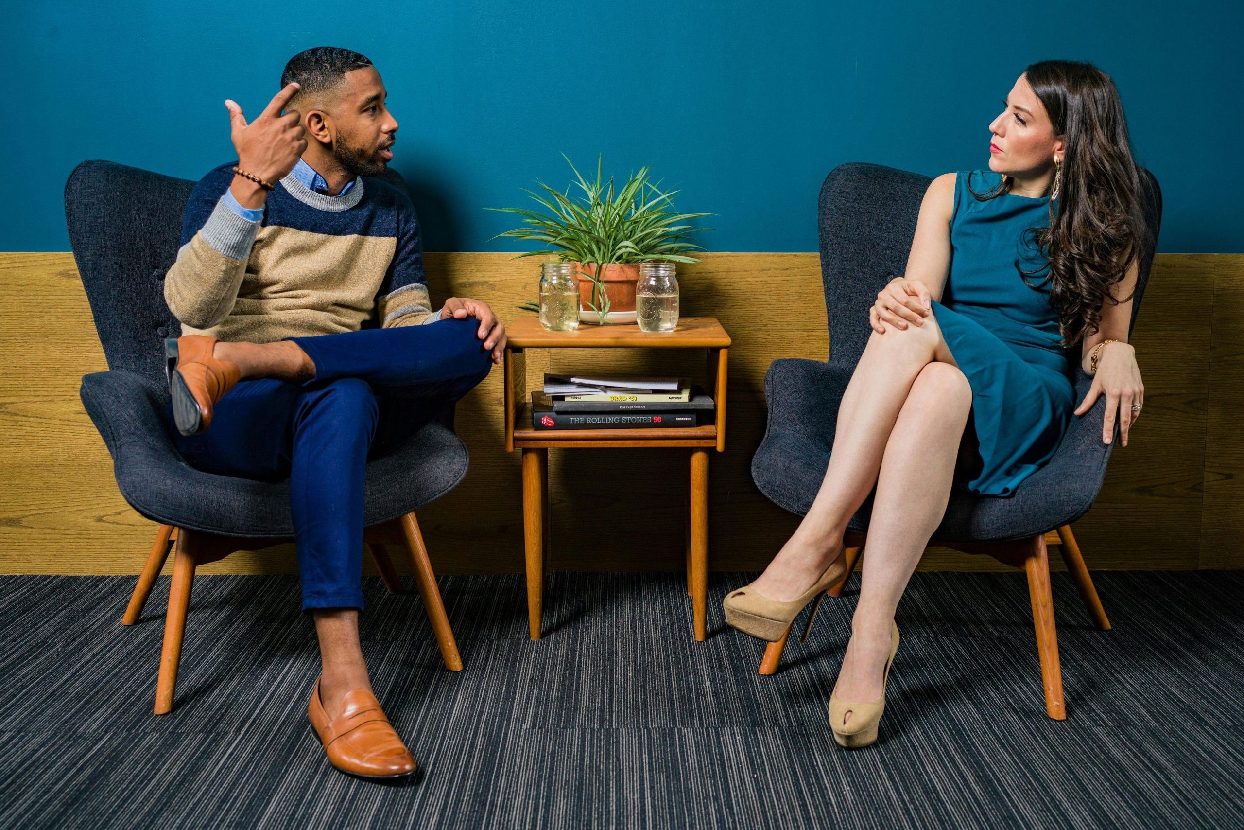 Two professionals in business attire engage in a thoughtful discussion sitting in a stylish, modern room.